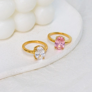 Polished gold stainless steel rings with oval pink and white zircon stones on a tray