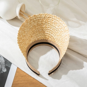 Top view of beige straw sun visor with an open-back design and woven texture on table