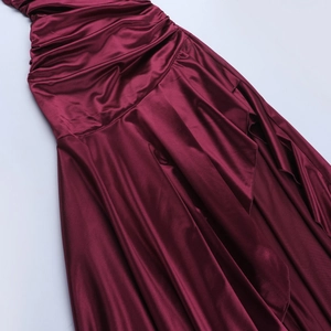 Makro-Detail des weinroten Satin-Kleides mit eleganten Falten und glänzender Stofftextur