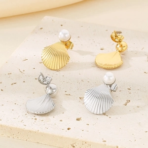 Detailed macro view of French style gold and silver shell-shaped pearl earrings on a stone