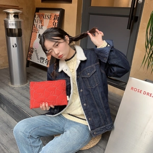 Outdoor shot of a red quilted rabbit clutch bag held by a model on stairs