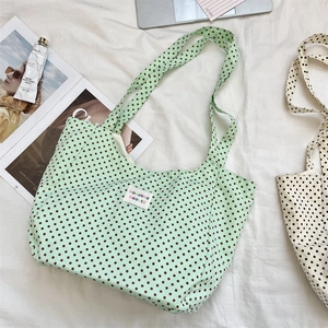 Close-up of mint green canvas tote bag with brown polka dots and woven brand label