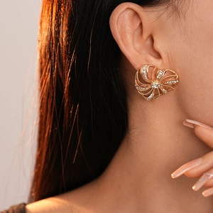 Close-up of golden heart windmill earring with pavé diamonds on a model's ear