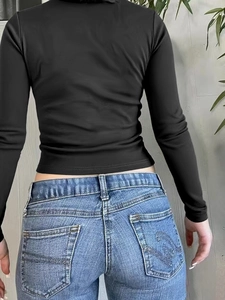 Rear view of a black long sleeve slim fit crop top paired with denim jeans for women