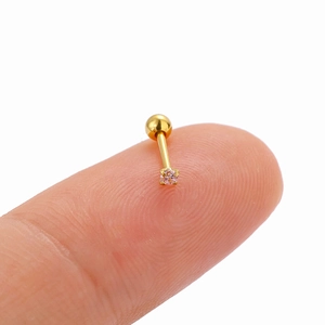 Macro shot of a minimalist gold stud earring with a pink zircon stone held on a fingertip