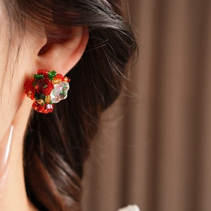 Macro shot of handmade floral earrings with vibrant red and green beaded petals