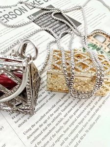 Detailed view of silver and gold rhinestone cube pendants on a vintage newspaper background