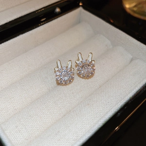 Macro shot of gold-plated rabbit stud earrings with zircon stones on white velvet