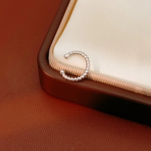 Macro shot of silver-tone twisted rope ear cuff featuring a textured C-shaped metal design