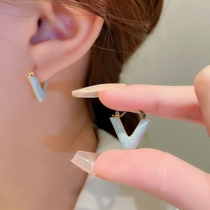 Detailed macro of light blue V-shaped earrings with fine glitter and gold finish