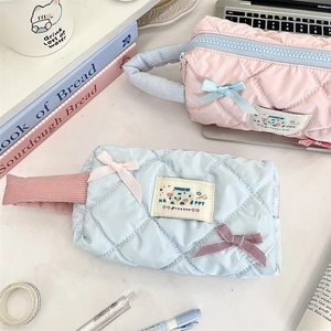 Detail of quilted pencil cases with bow accents and contrast handles in pink and blue