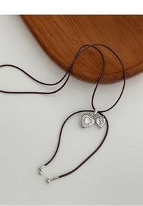 Macro shot of double heart pendant necklace with rhinestones and textured edges on wax cord