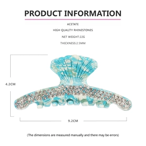 Detail view of shell-shaped blue marble acetate hair claw clip with rhinestones and specs
