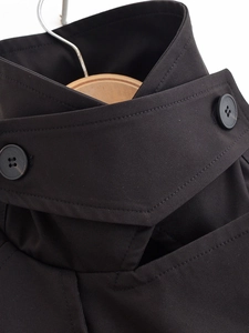 Close-up of double-breasted collar on a black trench coat with twill fabric detail