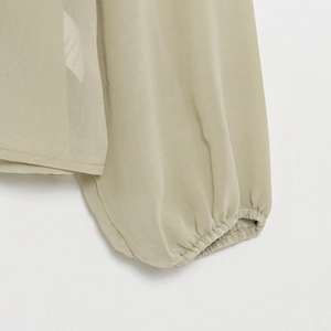 Close-up of translucent khaki shirt cuff with elastic wrist and textured fabric