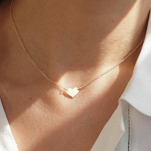 Gros plan d'un collier doré élégant avec pendentif en cœur porté sur un cou féminin