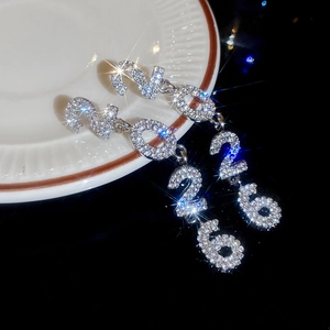Macro shot of silver-tone 2026 number earrings with shimmering rhinestones on black glass