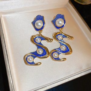 Makroaufnahme goldener Vintage-Schlangenohrringe mit blauem Emaille und Perlen in Box