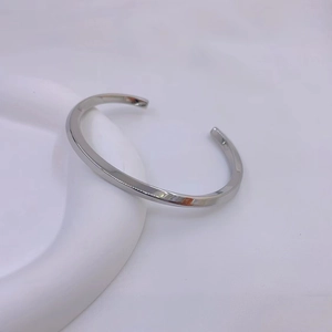 Close-up of polished silver Mobius twist cuff bracelet on a minimalist white stand