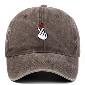 Detailed view of white finger heart embroidery and red heart on vintage washed baseball cap