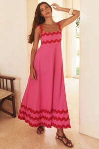 Detailed view of pink cotton maxi dress featuring decorative red wavy scalloped edge trim