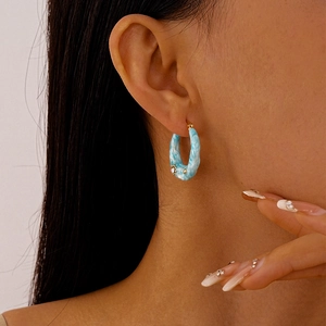 Detail of blue marble texture C-shape hoop earring with gold metal and rhinestones on model