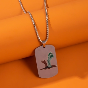 Detail of silver stainless steel dog tag necklace with zombie hand design on orange base