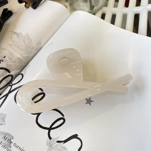 Close-up of a minimalist cream hair claw clip placed on an elegant magazine page