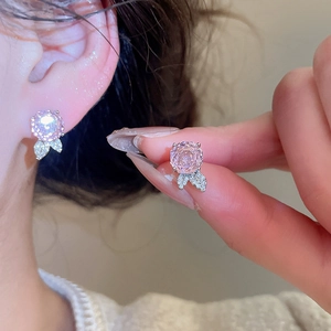 Nahaufnahme von rosa Zirkon-Blumenohrringen mit Silbernadel und funkelnden Details