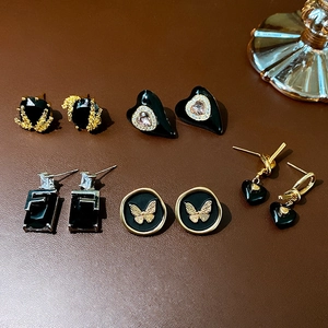Detailed flat lay of five assorted black and gold enamel heart earrings with zircons