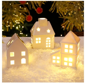 Detailed view of white ceramic LED Christmas houses with warm star-shaped cut-outs and snow