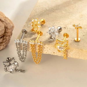 Titanium bowknot and chain labret studs with zircon settings on a stone surface