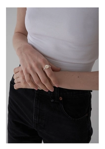 Detailed view of elastic freshwater pearl ring featuring a delicate daisy charm on finger
