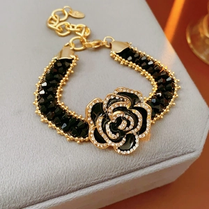 Detail of gold bracelet with black faceted beads and rhinestone rose on velvet box