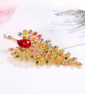 Macro detail of peacock brooch with vibrant multicolored rhinestones and red pear-cut stone