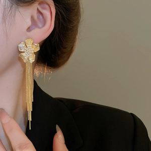 Close-up of 18k gold plated flower tassel earrings with pearls on model in black suit