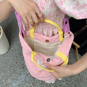 Détail de l'intérieur d'un sac cabas rose matelassé avec étiquette et anses jaunes