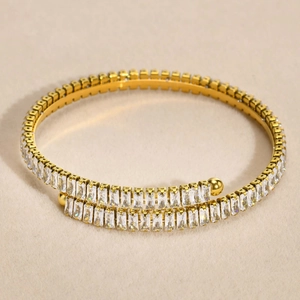 Bracelet jonc minimaliste en acier doré avec deux rangées de zircons carrés sur fond beige