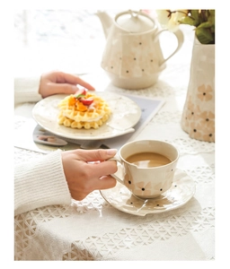 Détail d'une tasse à café en céramique artisanale avec fleurs roses et pois