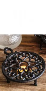 Macro shot of vintage cast iron tea warmer base with intricate hollow swirl patterns