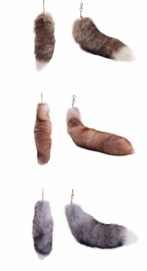 Detailed view of oversized fluffy fox fur tails in brown, red and grey with gold clasps