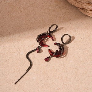 Detail of red moon earrings with gunmetal frame and asymmetric long chain tassels