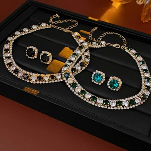 Detailed view of luxury gold necklace and earring sets with green and black crystals