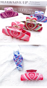Detail view of heart-shaped acrylic hair claws in pink and blue stripes for women