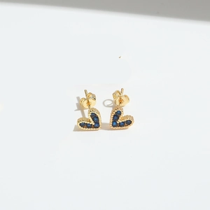 Close-up of heart stud earrings with blue cubic zirconia and gold-plated micro-beading