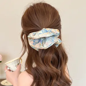 Detailopname van een bloemen kant scrunchie in lichtblauw op golvend bruin haar
