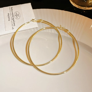 Boucles d'oreilles créoles dorées avec cristaux présentées sur un plat en céramique blanc