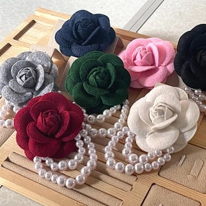 Multicolor camellia flower brooches with pearls in a wooden display showcase