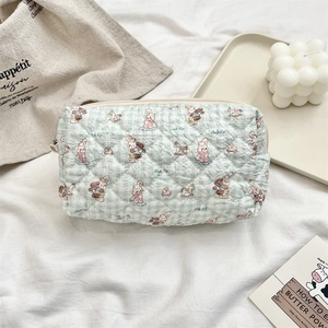 Detail of light blue quilted makeup bag with cute cartoon animal prints and zipper