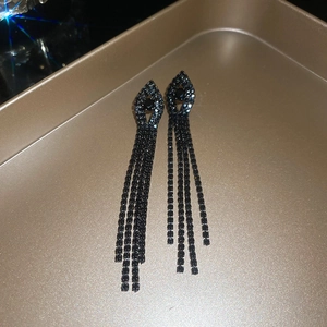 Macro shot of black tassel earrings with rhinestones on a gold tray with starburst light